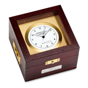 Wempe ship's chronometer in mahogany-colored wooden case with polished brass housing and white dial.